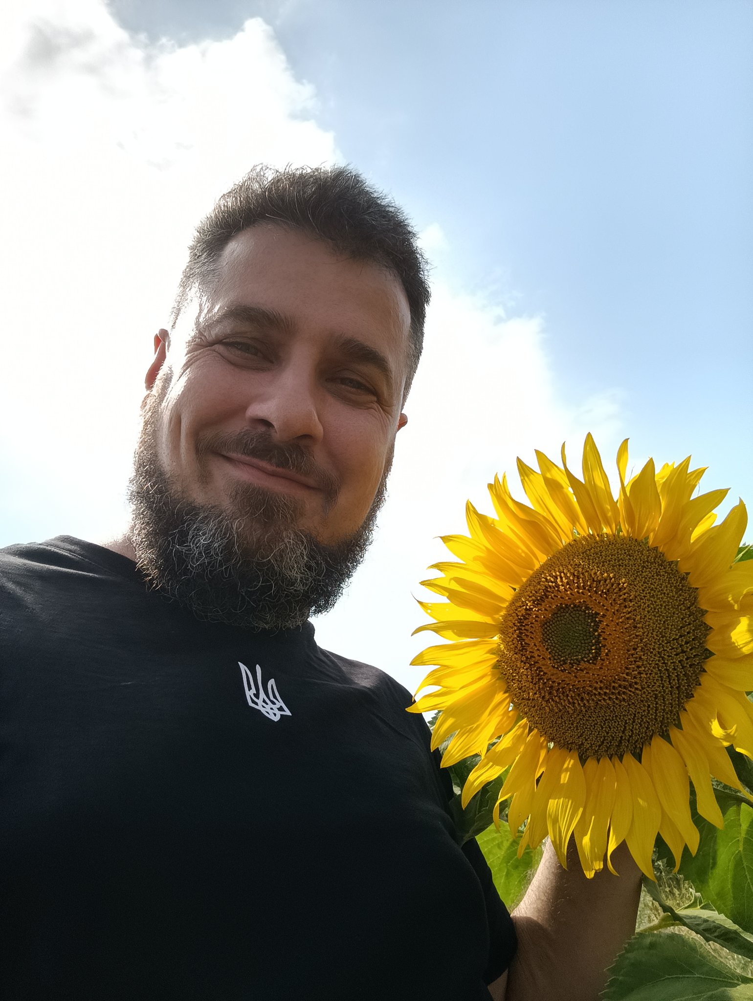 Ukrainian author Oleg Veretskiy, standing next to a beautiful sunflower.