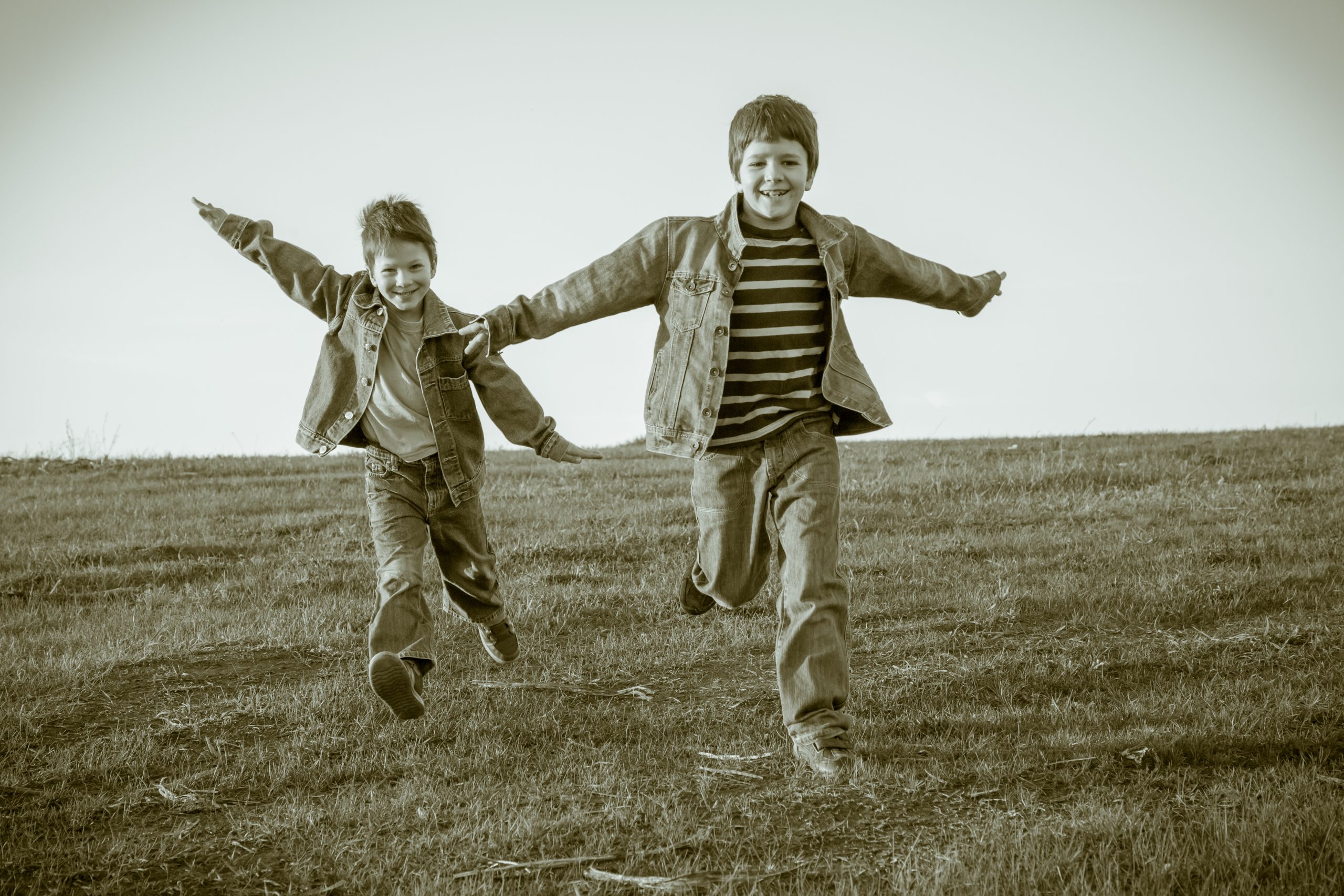 Vintage photo of 2 pre-teen boys running through a field toward viewer/camera.